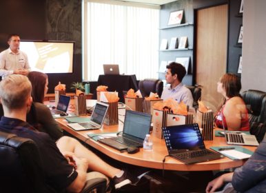 man standing in front of people sitting beside table with laptop computers