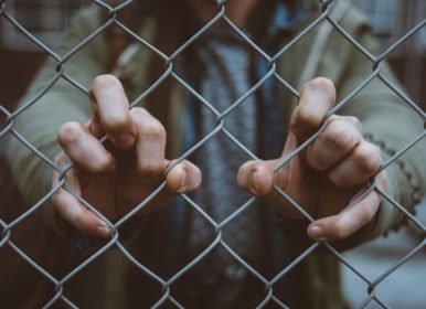 person behind mesh fence