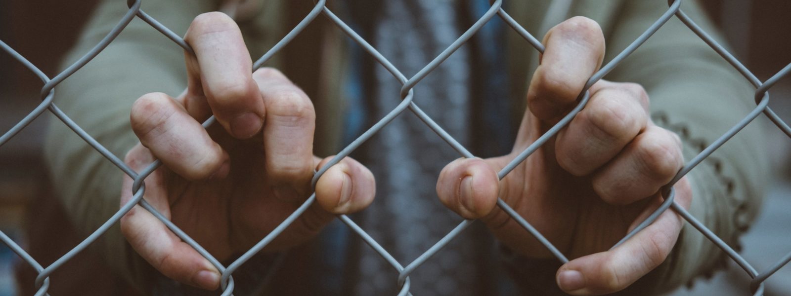 person behind mesh fence