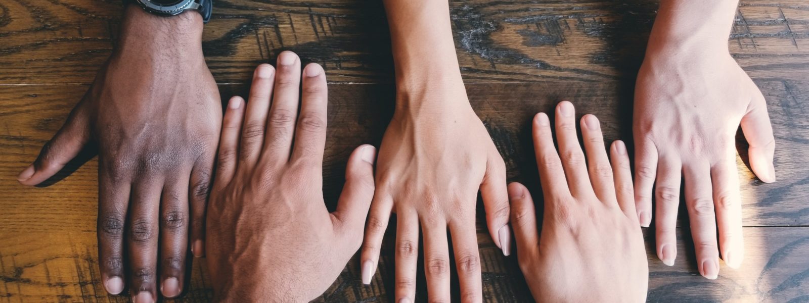 five human hands on brown surface